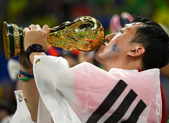 (221205) -- DOHA, Dec. 5, 2022 -- A fan of South Korea kisses a replica of the FIFA World Cup, WM, Weltmeisterschaft, Fussball Trophy before the Round of 16 match between Brazil and South Korea at the 2022 FIFA World Cup at Ras Abu Aboud (974) Stadium in Doha, Qatar, Dec. 5, 2022. ) (SP)QATAR-DOHA-2022 WORLD CUP-ROUND OF 16-BRA VS KOR LixGa 