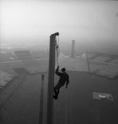Tall Task Tall Task Leopold Viallet , of the alpine guides , high above the Olympic Stadium in Grenoble climbs down the 90 Ft Olympic mast after checking the final assembly of the mast from which the giant flag wii fly after being raised at the opening of the 1968 Winter Olympics 2nd February 1968 France  Copyright: xTopFotox UPI550179-B
