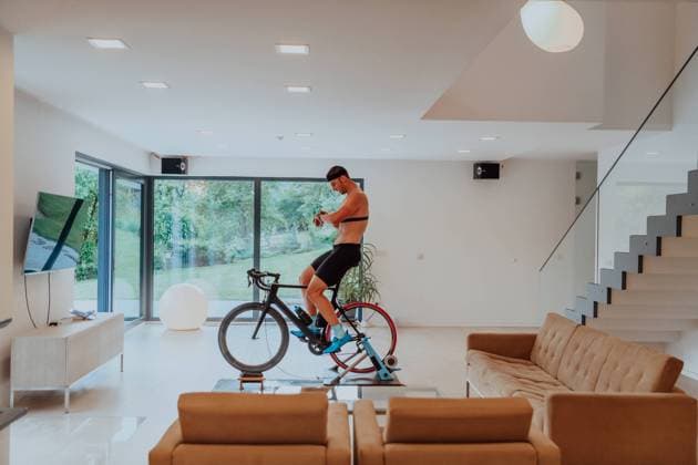 A man riding a triathlon bike on a machine simulation in a modern living room. Training during pandemic conditions. A man riding a triathlon bike on a machine simulation in a modern living room. Training during pandemic conditions (License=RF) 19511643 Copyright: xZoonar.com BENISxARAPOVICx 19511643 ,model released, Symbolfoto ,property released