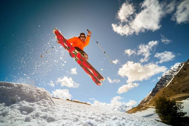 Fly young caucasian man jumping from a springboard on skis Beautiful young caucasian man in an orange jacket and black shorts jumping from a springboard on red skis against the background of mountains, sky, clouds, sun (License=RF) 18191459 ,model released, Symbolfoto Copyright: xZoonar.com IanxIankovskiix 18191459 ,model released, Symbolfoto ,property released