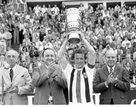 DFB Pokalfinale 1973: Borussia Mönchengladbach - 1. FC Köln 2:1 Mannschaftskaptän Herbert Hacki Wimmer (BMG) hebt den Pokal hoch. Links: Außenminister Hans-Dietrich Genscher und DFB-Präsident Dr. Hermann Gösmann. Überreichung; Siegerehrung *** DFB Cup Final 1973 Borussia Mönchengladbach 1 FC Köln 2 1 Team captain Herbert Hacki Wimmer BMG lifts the trophy Left Foreign Minister Hans Dietrich Genscher and DFB President Dr Hermann Gösmann presentation award ceremony HM