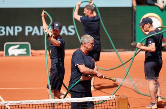 Workers hold a hose as they spray water onto the court to dampen the clay during world number 2 seeded Daniil Medvedev of Russia s first-round match against Thiago Seyboth Wild of Brazil at Roland Garros French Tennis Open in Paris, France, on Tuesday, May 30, 2023.  PAR20230530130 MAYAxVIDON-WHITE