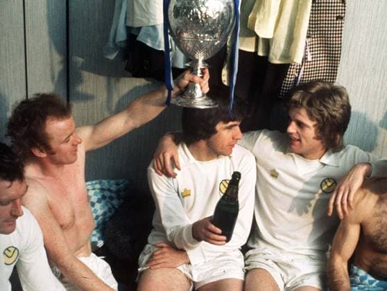 Football - 1973 1974. Leeds United v Sunderland. Billy Bremner Testimonial. 06 05 1974. The Leeds team relax in the dressing room with the League Championship trophy. Billy Bremner,lifts the trophy,with Peter Lorimer and Gordon McQueen. 