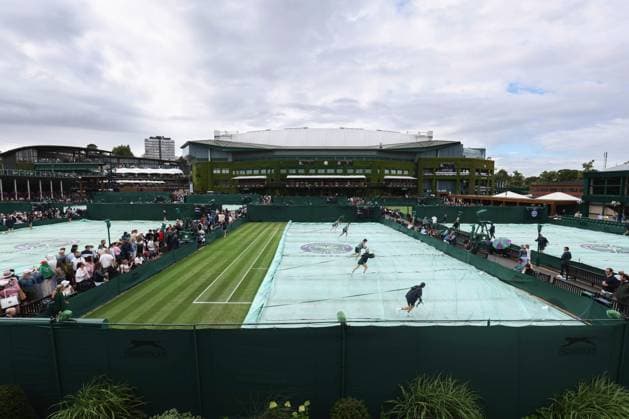 Wimbledon: Day One 3 July 2023, Wimbledon - Wimbledon Tennis Championships - Day One - Grounds staff pull the waterproof covers off of the outside court with Centre Court looming in the distance - Photo: Charlotte Wilson Offside . Wimbledon UK Copyright: xCharlottexWilsonx xOffsidexOffside