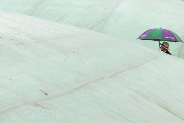 Sport Bilder des Tages Wimbledon: Day Three 5 July 2023, Wimbledon - Wimbledon Tennis Championships - Day Three - a steward with an umbrella walks between covered courts - Photo: Charlotte Wilson Offside . Wimbledon UK Copyright: xCharlottexWilsonx xOffsidexOffside