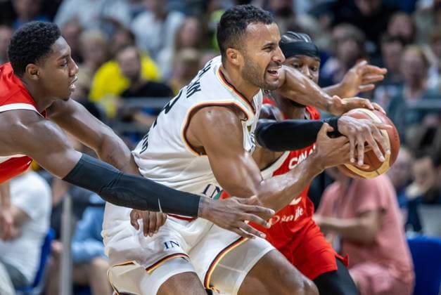 Basketball: Laenderspiele, Deutschland - Kanada, Mercedes-Benz Arena. Deutschlands Johannes Thiemann (M) kaempft gegen Shai Gilgeous-Alexander (r) aus Kanada um den Ball. Basketball: Laenderspiel Deutschland - Kanada