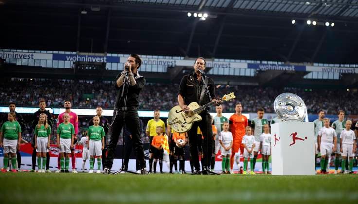 18.08.2023, Fussball 1. Bundesliga 2023 2024, 1. Spieltag, SV Werder Bremen - FC Bayern München, im Wohninvest Weserstadion Bremen. Sänger von Boss Hoss performen die Deutsche Nationalhymne vor dem Spiel auf dem Platz, Alec Völkel, Gesang, Rhythmusgitarre, Sascha Vollmer