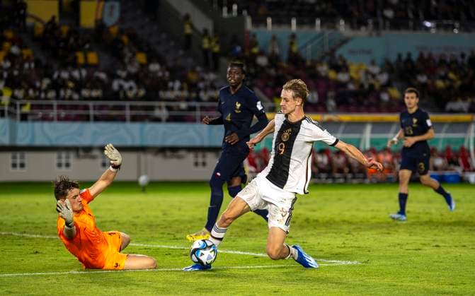02.12.2023, Fussball U-17-Weltmeisterschaft 2023, Finale: Deutschland - Frankreich, im Manahan Stadium (Surakarta). Max Moerstedt (re, Deutschland) wird gleich von Torwart Paul Argney (Frankreich) gefoult.