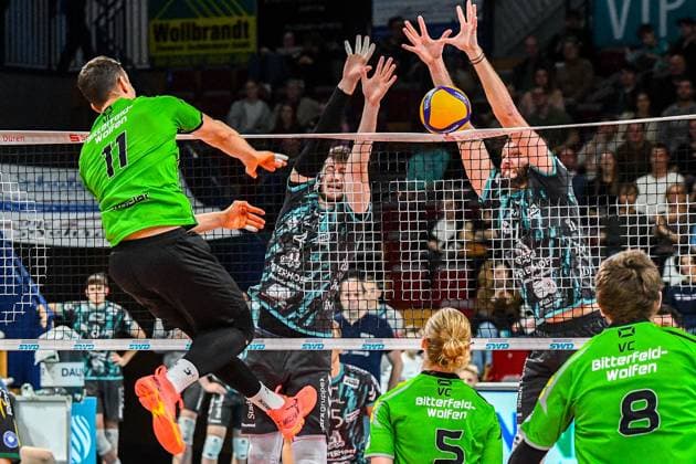 v.li.: Sebastian Lucas Rösler (Bitterfeld-Wolfen, 11) mit einem Schmetterball gegen den Block von Petr Spulak (Powervolleys Düren, 4) und Frixos Kotsakis (Powervolleys Düren, 7), Aktion, Action, Spielszene, 27.12.2023, Düren (Deutschland), Volleyball, 1. Bundesliga Männer, SWD Powervolleys Düren - BC Bitterfeld-Wolfen