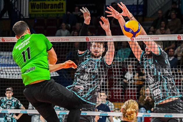 v.li.: Sebastian Lucas Rösler (Bitterfeld-Wolfen, 11) mit einem Schmetterball gegen den Block von Petr Spulak (Powervolleys Düren, 4) und Frixos Kotsakis (Powervolleys Düren, 7), Aktion, Action, Spielszene, 27.12.2023, Düren (Deutschland), Volleyball, 1. Bundesliga Männer, SWD Powervolleys Düren - BC Bitterfeld-Wolfen