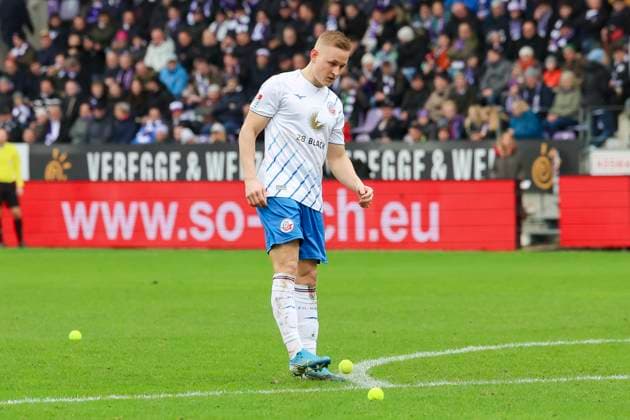 Kai Proeger (Hansa Rostock) schiesst einen von den Fans als Protest gegen den Investoreneinstieg bei der Deutschen Fussball Liga geworfenen Tennisball vom Rasen, 2. Bundesliga, VfL Osnabrueck vs Hansa Rostock, Bremer Bruecke, 11.02.2024, Osnabrueck, Deutschland.