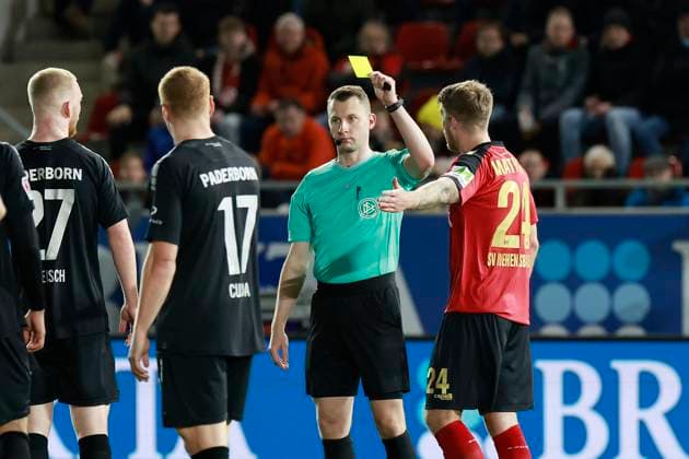 23.02.2024, xavx, Fussball 2.Bundesliga, SV Wehen Wiesbaden - SC Paderborn 07 emspor, v.l. Referee Schiedsrichter Florian Lechner zeigt die Gelbe Karte fuer, shows yellow card to Marcus Mathisen (SV Wehen Wiesbaden) (DFL DFB REGULATIONS PROHIBIT ANY USE OF PHOTOGRAPHS as IMAGE SEQUENCES and or QUASI-VIDEO) Wiesbaden