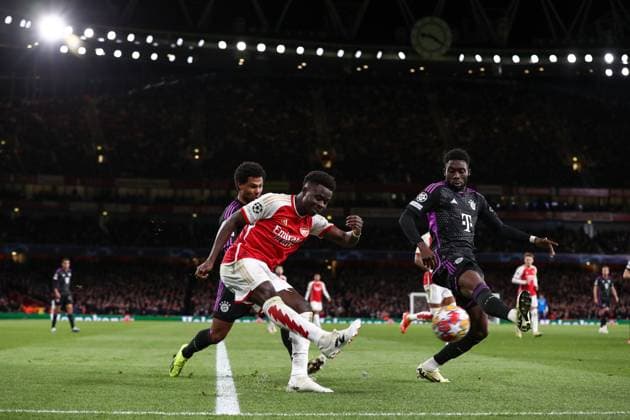 Arsenal v Bayern Munich 09 April 2024, London - UEFA Champions League - Quarter Final - First leg - Arsenal v Bayern Munich - Bukayo Saka of Arsenal crosses the ball past Alphonso Davies of Bayern Munich - Photo: Jacques Feeney Offside. London UK Copyright: xJacquesxFeeneyx xOffsidexOffside