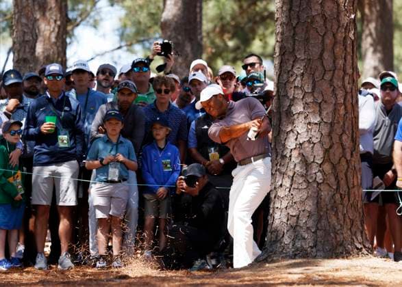 Patrons watch Tiger Woods hit his second shot on the 9th hole from behind a tree during the second round of the Masters Tournament at Augusta National Golf Club in Augusta, Georgia on Friday, April 12, 2024. Woods finished the day at one-over-par.  AUG202404121001 JOHNxANGELILLO