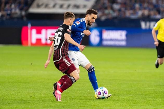 GER, 2. FBL, FC Schalke 04 vs 1.FC Nürnberg Nuernberg 13.04.2024, Veltins-Arena, Gelsenkirchen, GER, 2. FBL, FC Schalke 04 vs 1.FC Nürnberg Nuernberg Im Bild: Zweikampf zwischen Kenan Karaman (FC Schalke 04, 19); Lukas Schleimer (1.FC Nürnberg Nuernberg, 36) Ganzkörper Ganzkoerper ; Ball am Fuss;