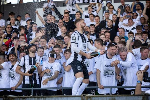 Die Spieler des SSV Ulm feiern zusammen mit Ihren Fans auf der Tribuene den Aufstieg in die 2. Fussball Bundesliga. Ganz vorne dabei Johannes Reichert (SSV Ulm 1846, 05) mit dem Champagner. ¨¨GER, SSV Ulm 1846 Fussball vs. FC Viktoria Koeln, Fußball, 3. Liga, 36. Spieltag, Spielzeit 2023 2024, 04.05.2024, ¨DFB DFL regulations prohibit any use of photographs as image sequences and or quasi-video.,¨ SSV Ulm 1846 Fussball - FC Viktoria Koeln , Fußball, 3. Liga, 36. Spieltag, Spielzeit 2023 2024, 04.05.2024 Ulm
