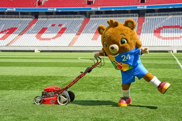 Munich, Bavaria, Germany - May 13, 2024: The mascot of UEFA EURO, EM, Europameisterschaft,Fussball 2024, a teddy bear called Albärt. Mascot of the European Championship, EM, Europameisterschaft symbolically mows the lawn of the Allianzarena pitch in Munich