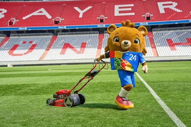 Munich, Bavaria, Germany - May 13, 2024: The mascot of UEFA EURO, EM, Europameisterschaft,Fussball 2024, a teddy bear called Albärt. Mascot of the European Championship, EM, Europameisterschaft symbolically mows the lawn of the Allianzarena pitch in Munich