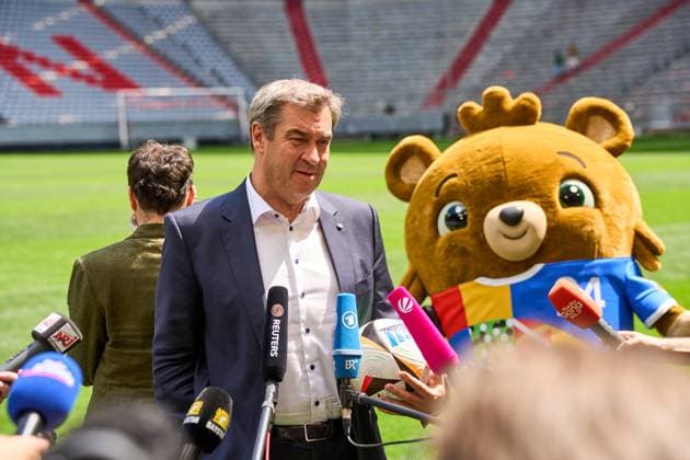 Munich, Bavaria, Germany - 13 May 2024: Prime Minister Dr. Markus Söder (CSU) on the soccer pitch at the Allianz Arena in Munich. He gives an interview, next to him stands the mascot of the European Championship, EM, Europameisterschaft 2024, Albärt