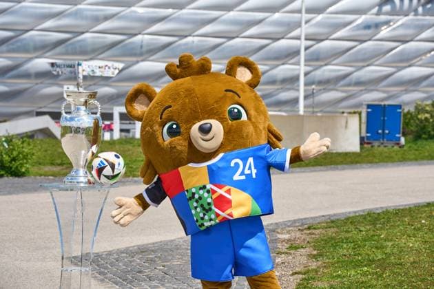 Munich, Bavaria, Germany - May 13, 2024: UEFA EURO, EM, Europameisterschaft,Fussball 2024 mascot Albärt with the Adidas match ball and the Henri Delaunay Cup in front of the Allianz Arena in Munich