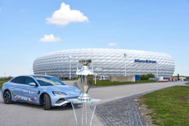Munich, Bavaria, Germany - May 13, 2024: BYD e-car with UEFA logo in front of the Allianz Arena soccer stadium in Munich together with the winner s trophy, Henri Delaunay Cup . Official e-mobility partner of UEFA EURO, EM, Europameisterschaft,Fussball 2024