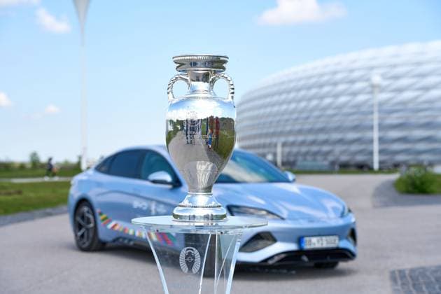 Munich, Bavaria, Germany - May 13, 2024: BYD e-car with UEFA logo in front of the Allianz Arena soccer stadium in Munich together with the winner s trophy, Henri Delaunay Cup . Official e-mobility partner of UEFA EURO, EM, Europameisterschaft,Fussball 2024