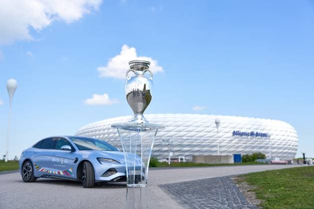 Munich, Bavaria, Germany - May 13, 2024: BYD e-car with UEFA logo in front of the Allianz Arena soccer stadium in Munich together with the winner s trophy, Henri Delaunay Cup . Official e-mobility partner of UEFA EURO, EM, Europameisterschaft,Fussball 2024
