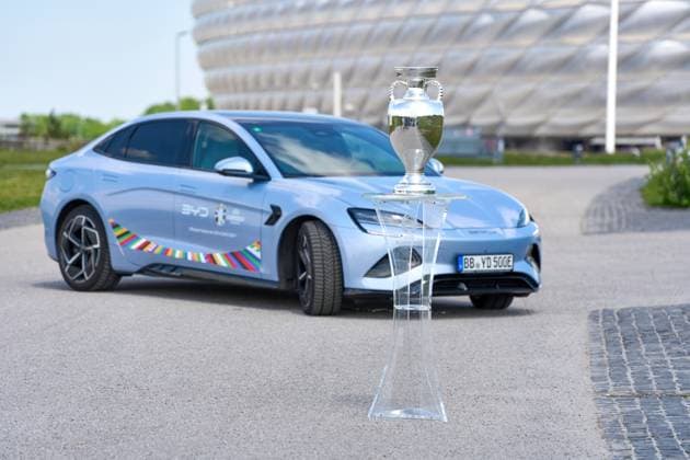 Munich, Bavaria, Germany - May 13, 2024: BYD e-car with UEFA logo in front of the Allianz Arena soccer stadium in Munich together with the winner s trophy, Henri Delaunay Cup . Official e-mobility partner of UEFA EURO, EM, Europameisterschaft,Fussball 2024