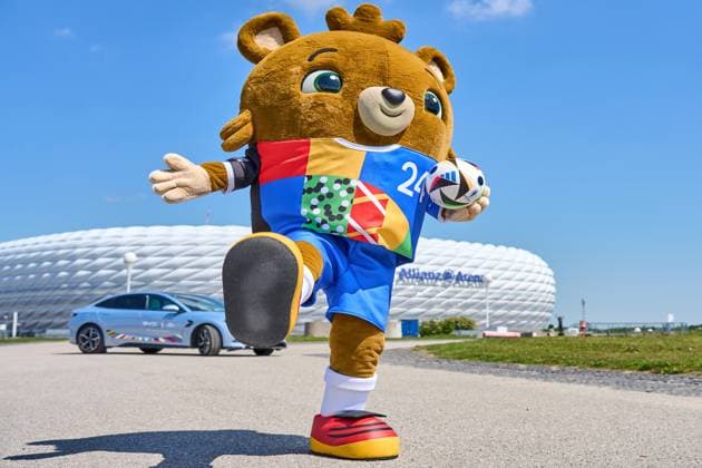 Munich, Bavaria, Germany - May 13, 2024: Mascot of the European Championship, EM, Europameisterschaft 2024 or European Football Championship in front of the Allianz Arena, with a BYD Seal electric car as sponsor and an Adidas match ball in the jersey