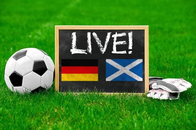 EURO 2024, Nationalteam Schottland, Fans in München 13 June 2024: European Football Championship 2024 Theme picture: Live broadcast of the match between Germany and Scotland Concept. A soccer with a board and gloves on the pitch with the inscription: Live! PHOTOMONTAGE