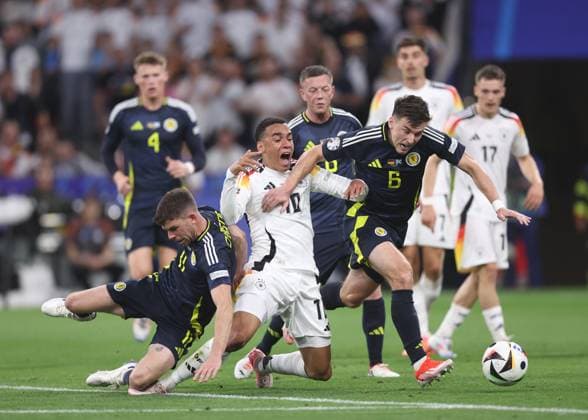 Munich, Germany, 14th June 2024. Ryan Christie of Scotland and Kieran Tierney of Scotland tackle Jamal Musiala of Germany during the UEFA European Championships match at Allianz Arena, Munich. Picture credit should read: David Klein Sportimage EDITORIAL USE ONLY. No use with unauthorised audio, video, data, fixture lists, club league logos or live services. Online in-match use limited to 120 images, no video emulation. No use in betting, games or single club league player publications. SPI-3194-0072