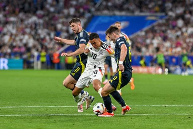EM 2024: Deutschland - Schottland am 14.06.2024 in der Allianz Arena in München Ryan Christie of Scotland im Zweikampf gegen Jamal Musiala (Deutschland) und Kieran Tierney of Scotland.