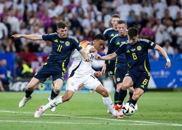 Muenchen, Allianz Arena, 19.09.2021: Jamal Musiala of germany (M) gets no penalty after this foul from Ryan Christie of scotland (L) and Kieran Tierney of scotland during the match UEFA European Championship, EM, Europameisterschaft 2024 Germany v. Scotland.