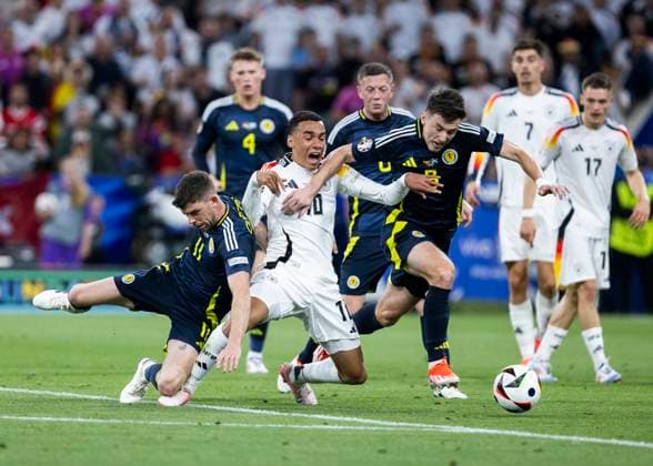 Muenchen, Allianz Arena, 19.09.2021: Jamal Musiala of germany (M) gets no penalty after this foul from Ryan Christie of scotland (L) and Kieran Tierney of scotland during the match UEFA European Championship, EM, Europameisterschaft 2024 Germany v. Scotland.