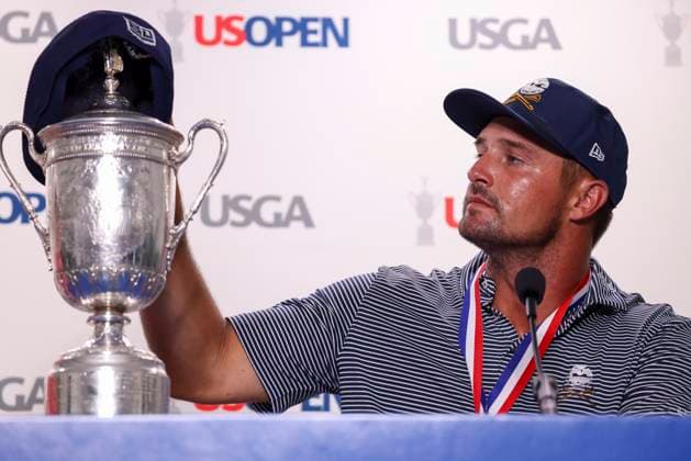 Bryson DeChambeau of the United States looks toward the championship trophy topped by golf flat cap, a style made popular by the late Payne Stewart, during a press conference, PK, Pressekonferenz to fans after winning the 124th US Open golf championship at Pinehurst Resort & Country Club in Pinehurst, N.C. on Sunday, June 16, 2024.  NCP202406168271 VeaseyxConway