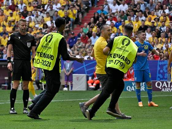 17.06.2024, Fussball UEFA EURO, EM, Europameisterschaft,Fussball 2024, Vorrunde, Match 10, Rumänien - Ukraine, in der Fußball Arena München. Ein Flitzer wird von zwei Ordnern vom Platz geführt