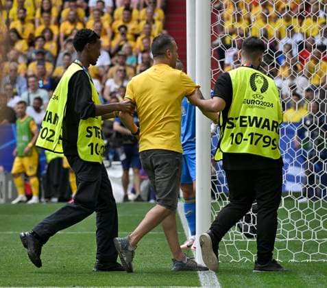 17.06.2024, Fussball UEFA EURO, EM, Europameisterschaft,Fussball 2024, Vorrunde, Match 10, Rumänien - Ukraine, in der Fußball Arena München. Ein Flitzer wird von zwei Ordnern vom Platz geführt
