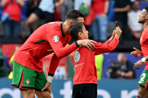 22.06.2024, xsltx, Fussball EM 2024, Türkei - Portugal emspor, v.l. Ein kleiner Junge macht ein Selfie mit Cristiano Ronaldo (Portugal) auf dem Feld und wird dann von Ordnern eingefangen. Handy, Smartphone, Flitzer, Kind (DFL DFB REGULATIONS PROHIBIT ANY USE OF PHOTOGRAPHS as IMAGE SEQUENCES and or QUASI-VIDEO) Dortmund