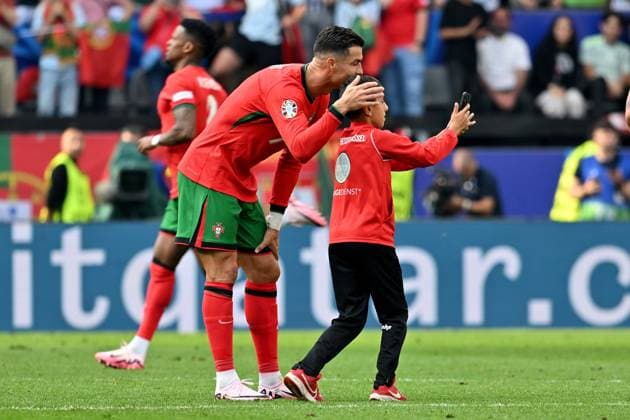 22.06.2024, xsltx, Fussball EM 2024, Türkei - Portugal emspor, v.l. Ein kleiner Junge macht ein Selfie mit Cristiano Ronaldo (Portugal) auf dem Feld und wird dann von Ordnern eingefangen. Handy, Smartphone, Flitzer, Kind (DFL DFB REGULATIONS PROHIBIT ANY USE OF PHOTOGRAPHS as IMAGE SEQUENCES and or QUASI-VIDEO) Dortmund