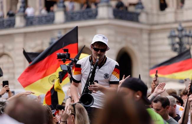 Deutschland - Hessen - Frankfurt am Main - 23.06.2024 Fußball Europameisterschaft 2024 EM-Typ mit dem Saxophon, Saxofonist im Völler-Trikot, Andre Schnura mit dem schwarzen Saxophon Public-Viewing in Frankfurt