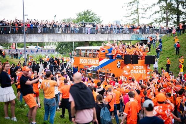 02.07.2024 - Fußball, Europameisterschaft 2024 in Deutschland, Fans in München Rumänien - Niederlande: Niederländische Fans vor dem Spiel beim Fanmarsch mit dem Bus in der Nähe des Olympiaparks. Passanten schauen von einer Brücke.