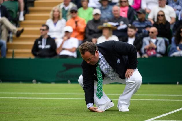 240702 An umpire checks the grass for moisture during day 2 of Wimbledon on July 2, 2024 in London. Photo: Jesper Zerman BILDBYRAN kod JZ JZ0548 tennis wimbledon AELTC day 2 bbeng Copyright: JESPERxZERMAN BB240702JZ125