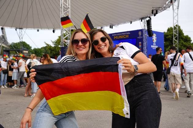 Munich, Bavaria, Germany - July 5, 2024: Public viewing in the fan zone in Munich s Olympiapark for the quarter-final of UEFA EURO, EM, Europameisterschaft,Fussball 2024 Germany vs. Spain. Two female fans with Germany flag and fan accessories