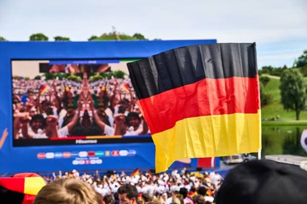Munich, Bavaria, Germany - July 5, 2024: Public viewing in the fan zone in Munich s Olympiapark for the quarter-final of UEFA EURO, EM, Europameisterschaft,Fussball 2024 Germany vs. Spain. Fan Germany flag in front of the big screen in the fan mile