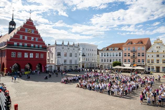Blick auf das Rathaus mit den Fans. 550 Menschen bilden eine Toni 8 zur Ehrung des Ausnahmespielers, der in der Hansestadt Greifswald geboren wurde. GER, Hansestadt Greifsald, Toni Kroos, Ehrung, HGW, Marktplatz, Fans, Fussball