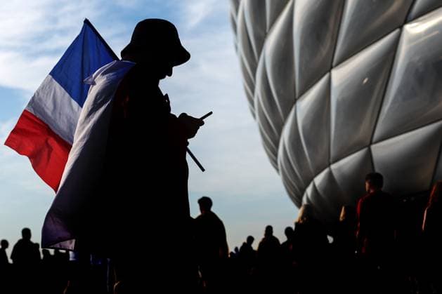Spain v France 9 July 2024, Munich - UEFA EUROs - Semi-Final - Spain v France - A France fan is silhouetted against the Allianz Arena as he checks his phone while holding a flag - Photo: Charlotte Wilson Offside. Munich Germany Copyright: xCharlottexWilsonx xOffsidexOffside
