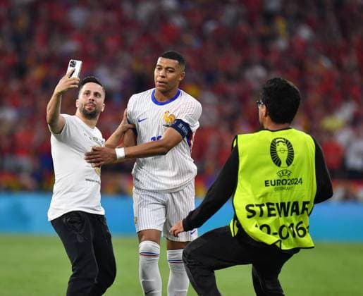 09.07.2024, Fussball UEFA EURO, EM, Europameisterschaft,Fussball 2024, Halbfinale, Spanien - Frankreich, in der Münchner-Fussball-Arena. Ein Flitzer bei Kylian Mbappe (Frankreich) er macht ein Selfie