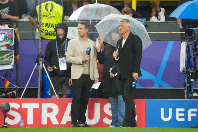 Die Moderatoren Alexander Bommes und Bastian Schweinsteiger unter den Schirmen bei Regen in Dortmund - Dortmund 10.07.2024: Niederlande vs. England, EURO2024 M50, Halbfinale, EM-Arena Dortmund