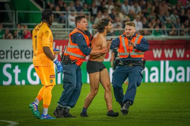 Fußball: FC St. Gallen 1879 vs. FC TOBOL KOSTANAY - 2. Qualifikationsrunde UEFA Conference League - Kybunpark St. Gallen, Schweiz: Ein halbnackte Flitzer macht ein Selfie Foto mit St. Gallens Torhüter Lawrence Ati Zigi und wird von Sicherheitskräften vom Spielfeld geführt. St. Gallen Kybunpark Kanton St. Gallen Schweiz Copyright: xJoeranxSteinsiekx