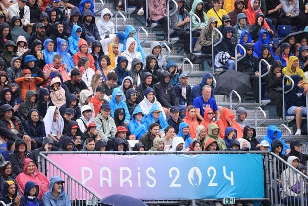 JO Paris 2024. Météo sur Volleyball de Plage (Beach Volley) JEUX OLYMPICS PARIS 2024 PHOTOPQR LE PARISIEN Olivier Arandel ; Paris ; 27 07 2024 ; 27 07 2024 - Paris -JO Paris 2024 - Épreuves de Volleyball de plage (Beach Volley) - Vue sur la Tour Eiffel sous une météo pluvieuses - (USA - CUBA) Partain Benesh (en blanc) contre Diaz Alayo (en bleu)- Arena Champs de Mars - Site de la Tour Eiffel - Les spectateurs ont enfilé les vêtements de pluie dans les gradins du stade de la Tour Eiffel LP Olivier Arandel - The Paris 2024 Summer Olympic Games, Olympische Spiele, Olympia, OS (Jul 26-Aug 11, 2024). Beach volleyball, Beachvolleyball - MEN S PRELIMINARY PHASE - POOL D MATCH 10 USE VS CUBA